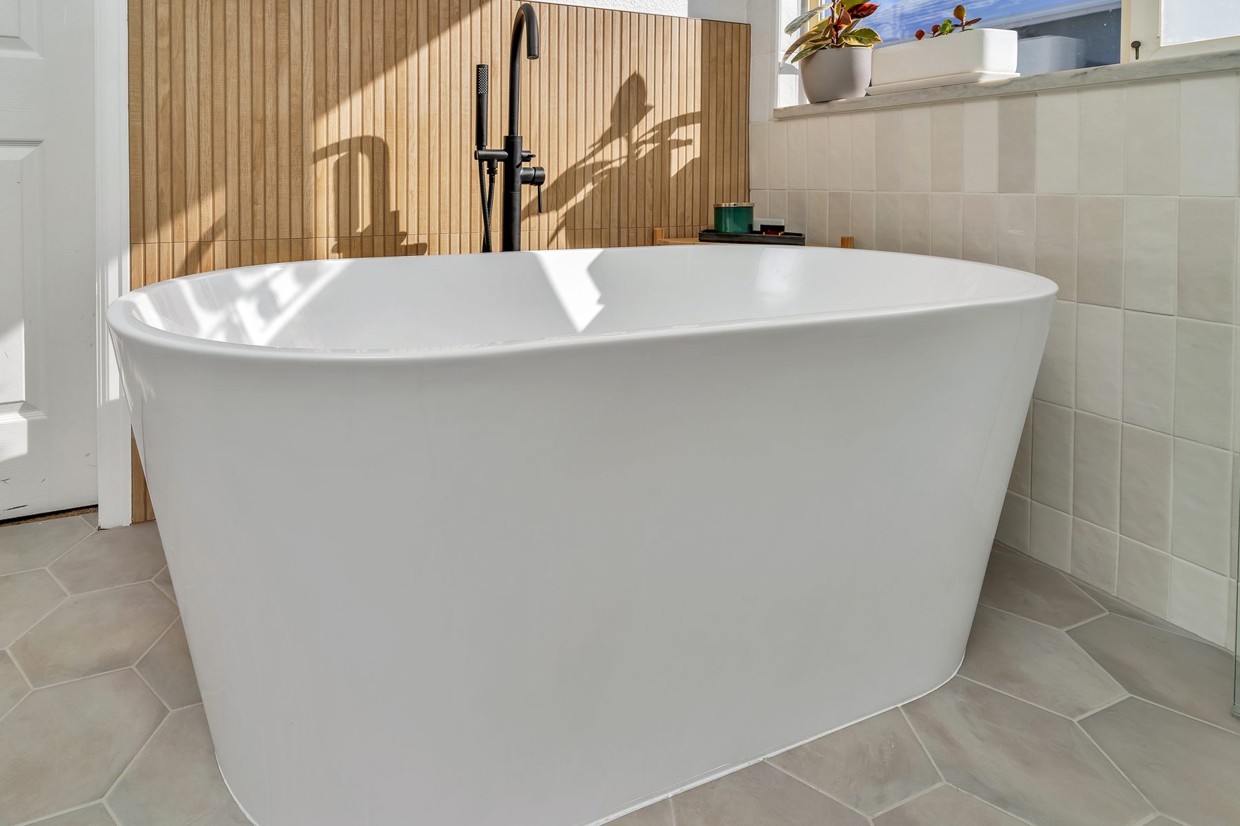 Spa bathroom with freestanding tub against a wood-slat accent wall